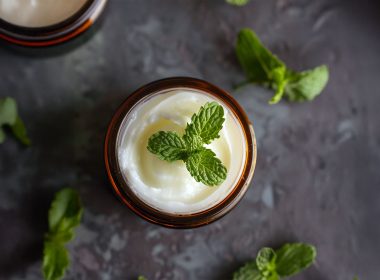 A jar of peppermint foot rub with a peppermint leaf on the top
