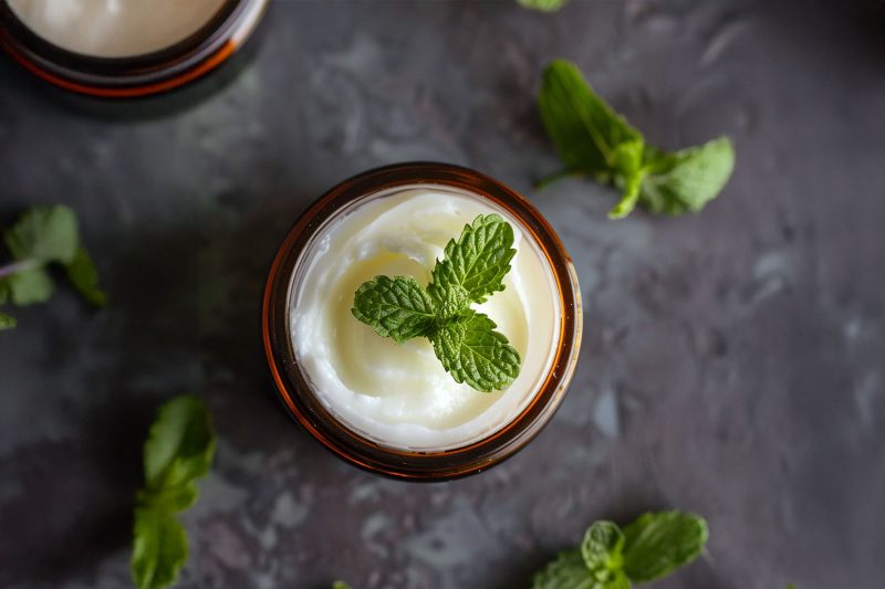 A jar of peppermint foot rub with a peppermint leaf on the top