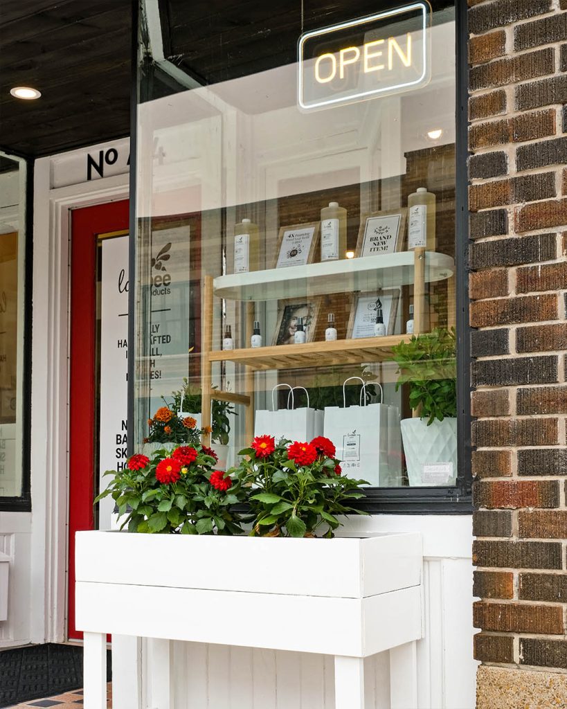An exterior shot of Lovebee Products showing a flower bed and open sign